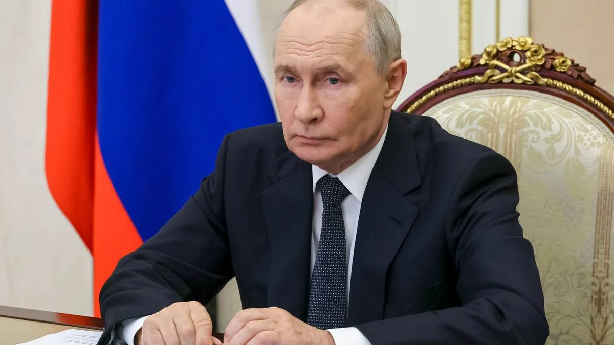 Володимир Путін сидить за столом на тлі російського прапора