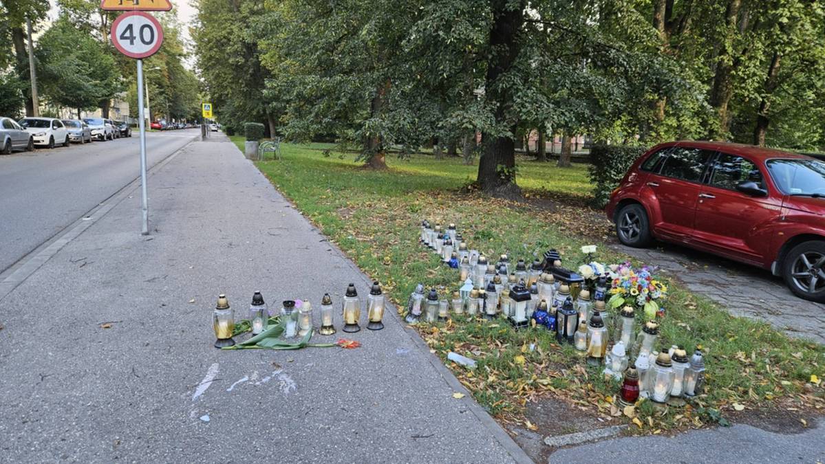 Меморіал зі свічками та квітами на узбіччі вулиці біля червоного авто