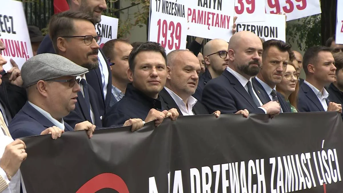 Чоловіки в костюмах тримають банер і плакати про 17 вересня 1939 і Катинь